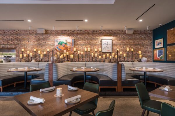 Upscale restaurant interior featuring custom curved booth seating, brick accent wall, and artistic decor by South Loft, creating a warm and inviting dining atmosphere in Texas hospitality spaces.