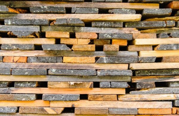 Stacked wood planks with natural bark edges, prepared for crafting bespoke furniture by South Loft, a Texas-based custom furniture maker for homes and hospitality spaces.