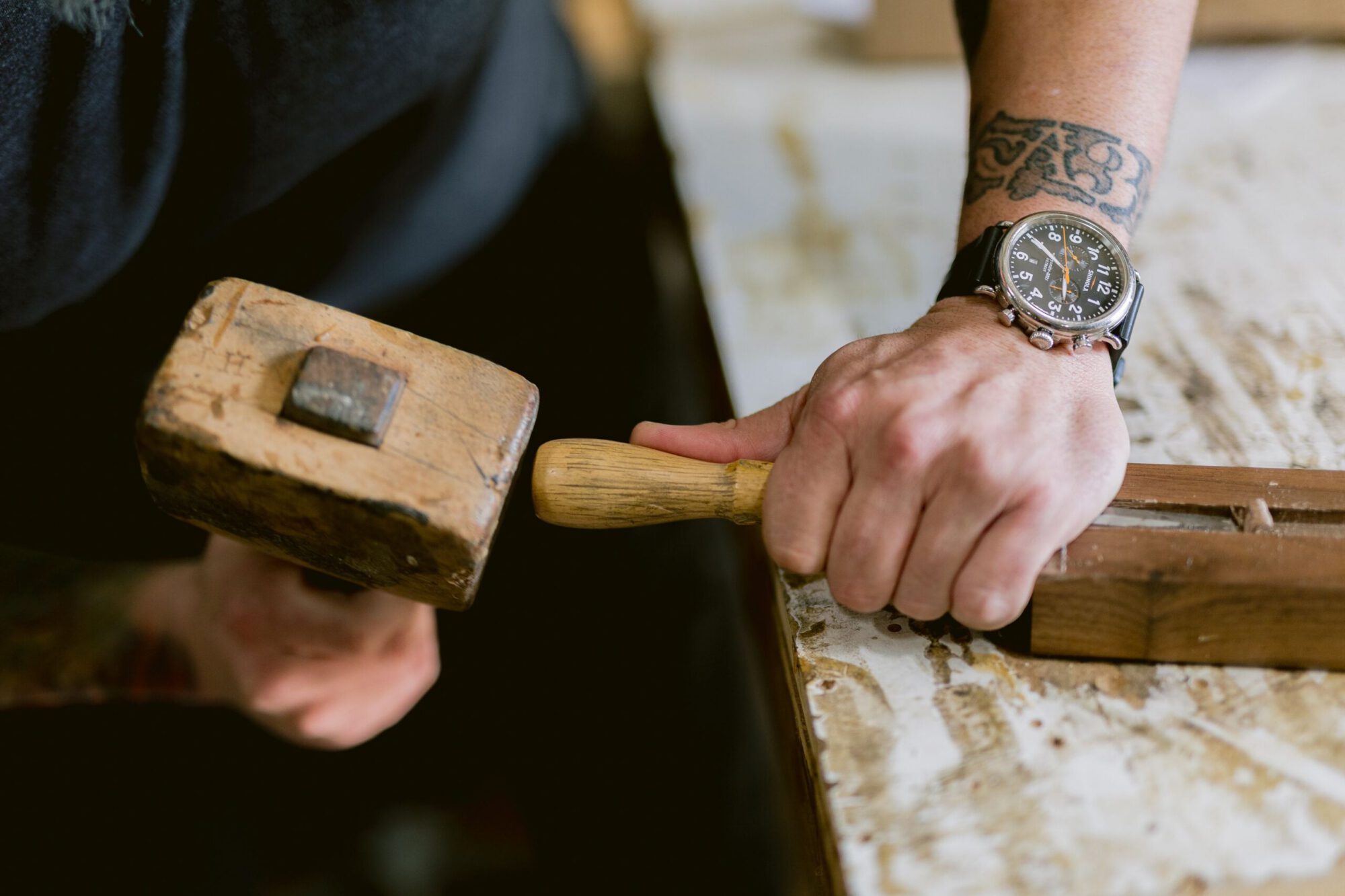 Close-up of a craftsman using a mallet and chisel to shape wood during the custom furniture-making process at South Loft, highlighting skilled woodworking for bespoke Texas interiors.