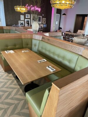 SouthLoft rectangular tabletop and custom booth seating with light green cushions and a wooden table in a modern dining area.