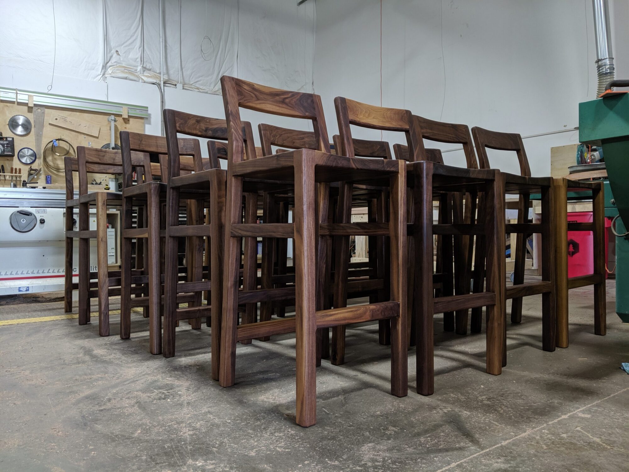 A group of walnut dining seats inside of SoutLoft''s workshop.