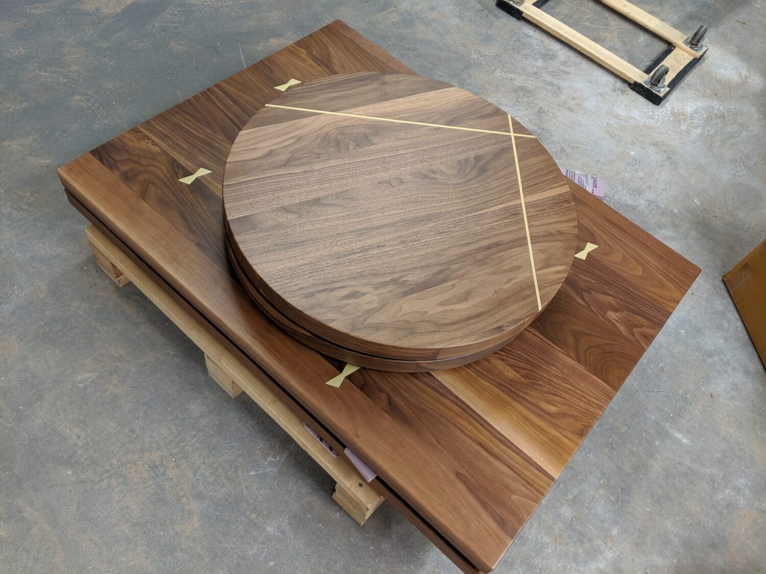A round tabletop and rectangular wooden tabletop stacked on top of each other, both featuring unique inlays and natural wood grain patterns.