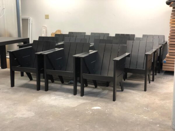 A group of black wooden chairs arranged neatly in a workshop setting.