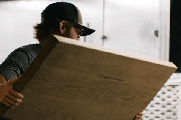 Craftsman carrying a custom wood slab during the furniture-making process at South Loft, highlighting expert woodworking and bespoke designs for Texas homes and businesses.