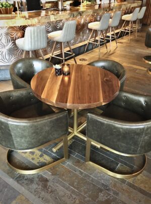 A SouthLoft built 120 Series round tabletop sits in a restaurant with green leather seating.