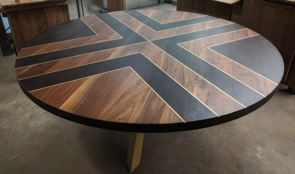 Custom round table by South Loft, featuring a striking geometric pattern with contrasting wood tones and brass inlays.