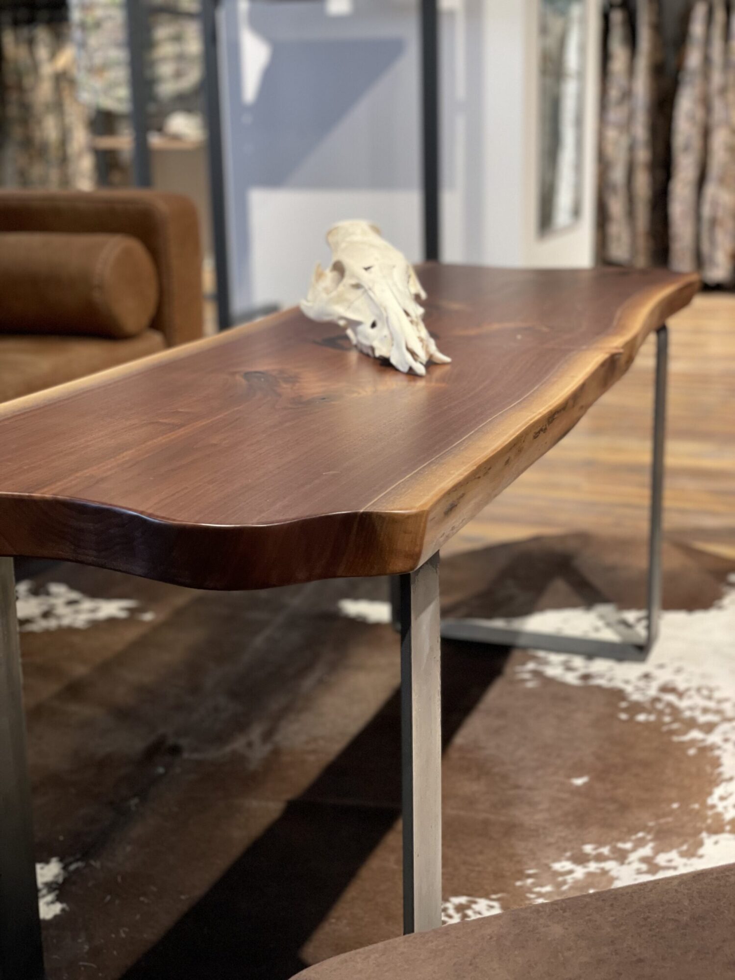 A live-edge tabletop with metal base sits inside of a commercial interior.