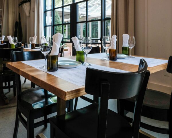 Elegant dining setup featuring custom-made wood tables and sleek black chairs by South Loft, designed for upscale restaurants and hospitality spaces in Texas.