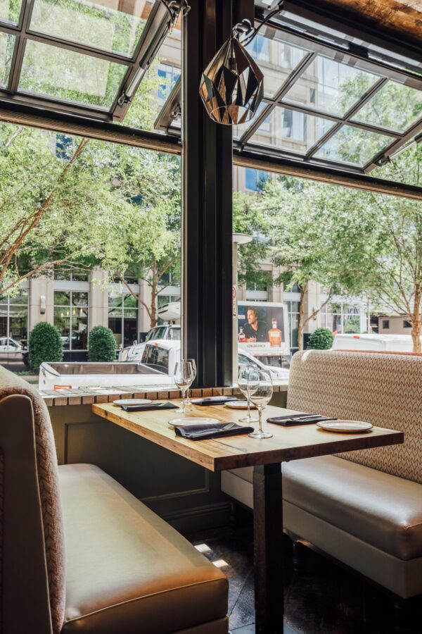 South Loft custom wooden table with booth seating in a bright dining area with large open windows.