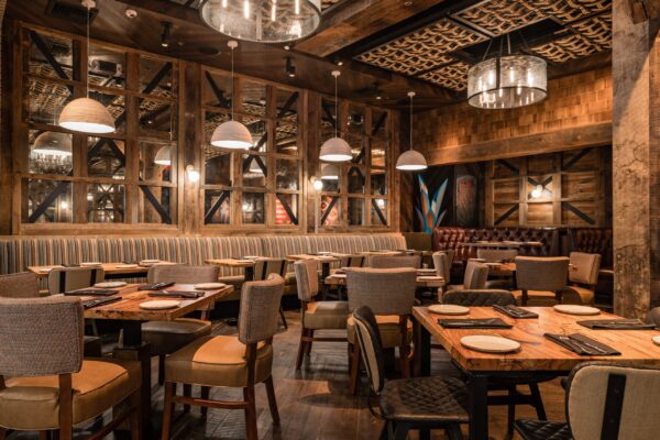 South Loft custom dining tables and chairs in a rustic restaurant with striped booth seating and industrial lighting.