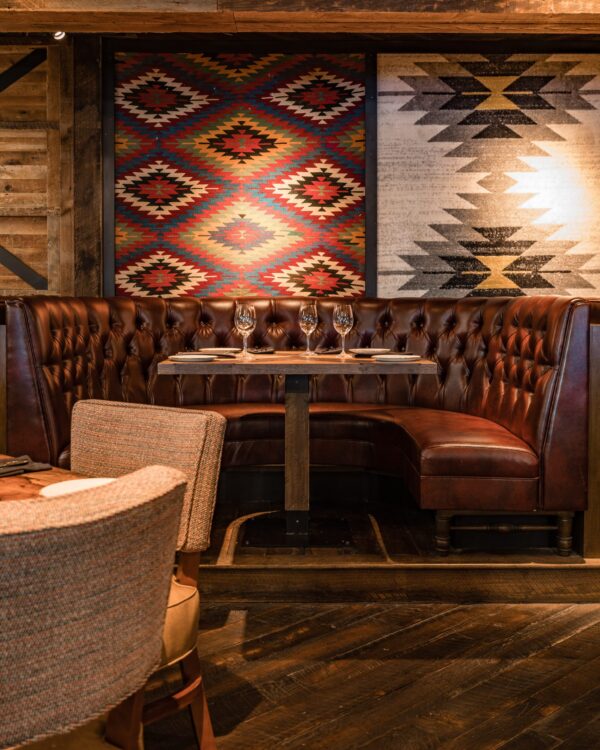 South Loft custom tufted leather booth with a wooden table in a rustic dining area with southwestern decor.