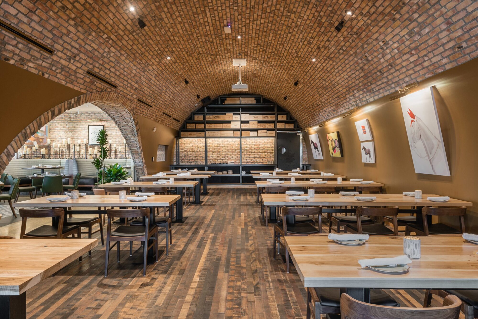 A dining area equipped with 110 Series rectangular commercial tabletops. The room has exposed brick arched ceilings and modern wooden tables and chairs at SouthLoft's custom furniture showcase.