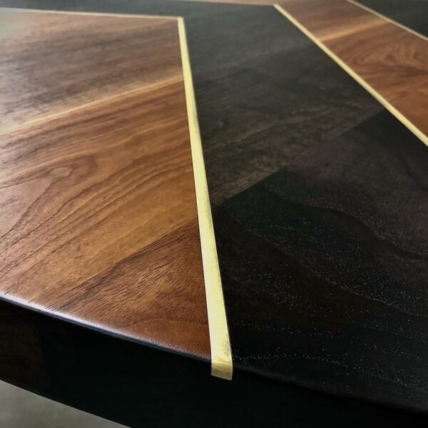 Close-up of a South Loft custom table featuring intricate wood grain and metal inlay details.