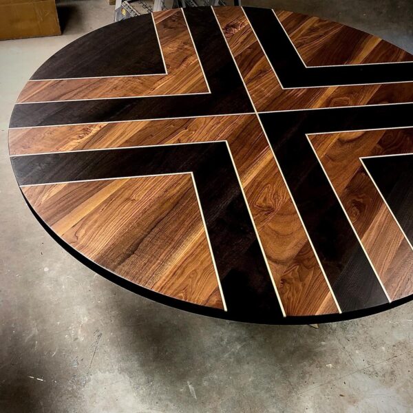 A South Loft round custom dining table with a striking geometric pattern of dark and light wood tones.