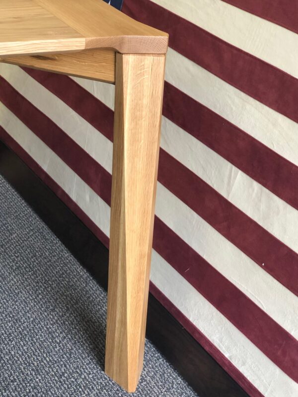 A detailed view of the handcrafted table leg from South Loft, showing the expert joinery and the natural wood grain against an American flag backdrop.
