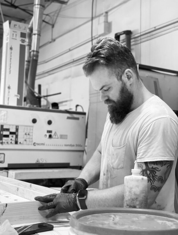 South Loft craftsman working on a wooden piece in the workshop, demonstrating precision and craftsmanship in the furniture-making process.