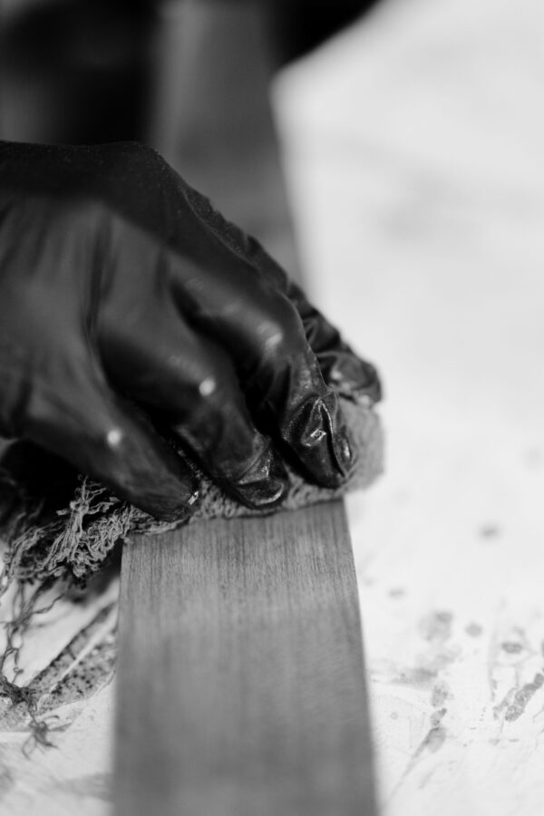 Close-up of a South Loft craftsman applying a finishing touch to a wooden piece with a soft cloth, showcasing the precision and care in the furniture-making process.