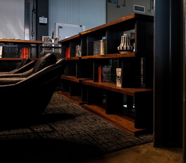 A modern custom bookshelf by South Loft featuring sleek black metal supports and rich wooden shelving, styled with books and decorative items.
