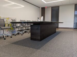 A modern, sleek conference table by South Loft, crafted in dark wood, set in a well-lit office meeting room, symbolizing South Loft's commitment to combining style and functionality.