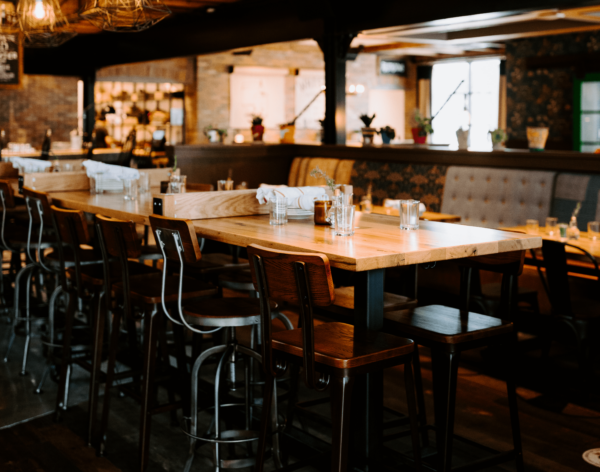 A stylish, rustic dining area featuring wooden high-top tables and industrial-style chairs, set in a warm, inviting atmosphere, custom-designed by South Loft.
