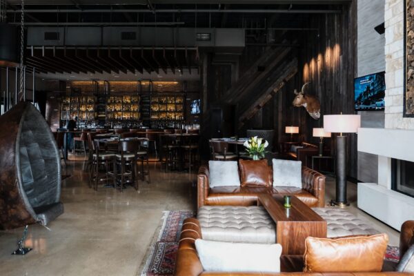 South Loft custom walnut bar and lounge furniture in a stylish, rustic-chic bar area with leather seating and mounted decor.