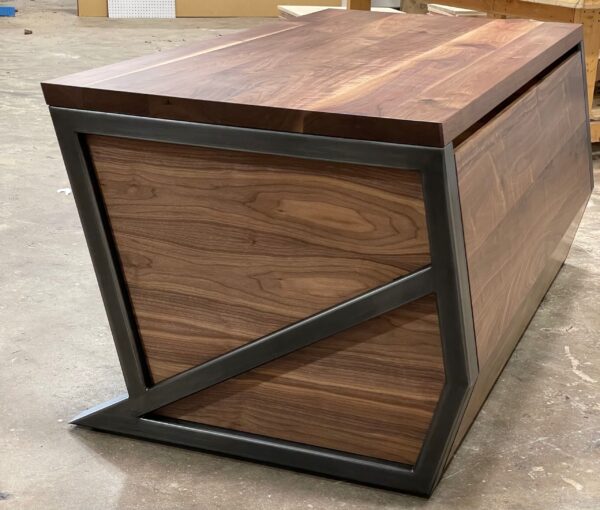 South Loft handcrafted executive desk with angular black metal frame and rich wood grain panels in a workshop setting.
