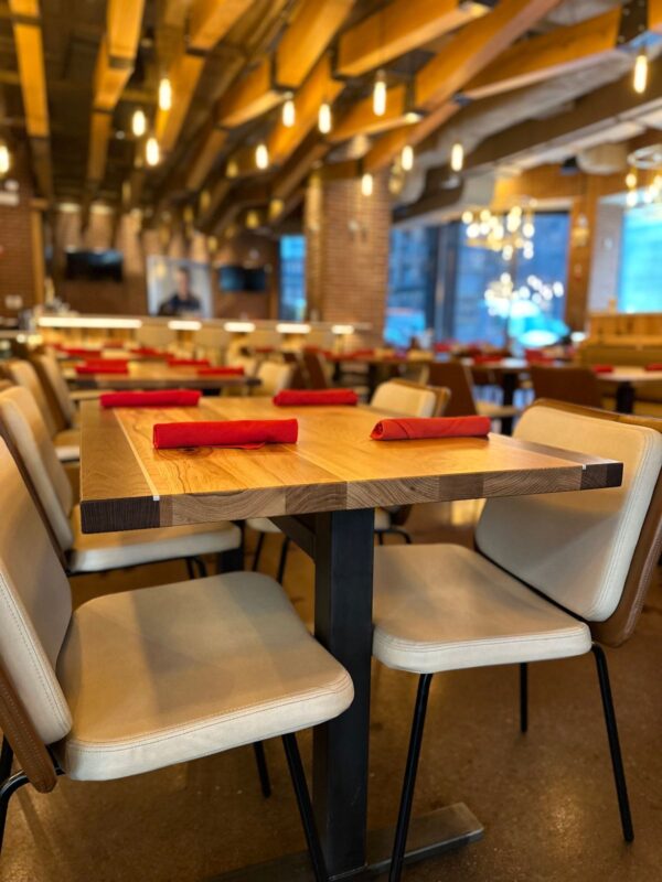 South Loft custom wood table and chairs in a restaurant, with overhead lighting and warm tones creating a cozy dining atmosphere.
