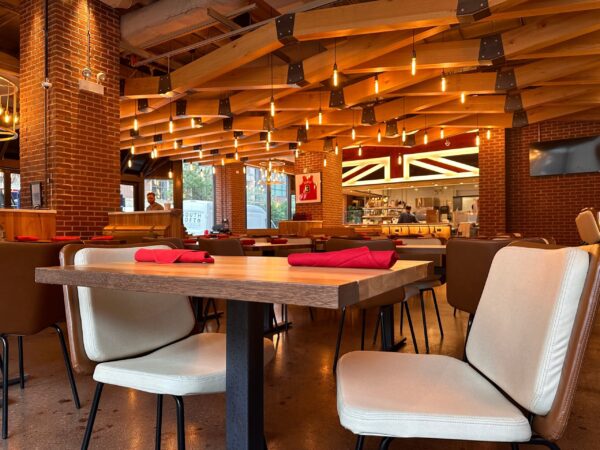 South Loft custom dining table and chairs with red napkins in a modern restaurant with exposed beams and brick walls.