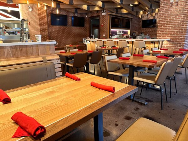 South Loft custom wooden tables and booth seating in a modern restaurant with red napkin place settings.