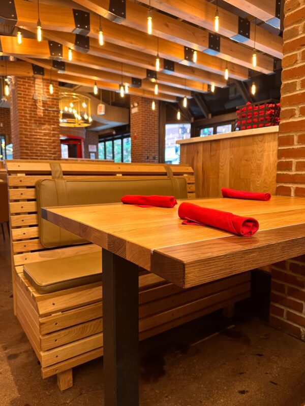 South Loft custom wooden booth seating and dining table with red napkins in a modern restaurant interior.