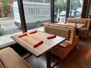 SouthLoft custom wooden booth seating with a rectangular dining table set with red napkins, and a SouthLoft van visible outside.