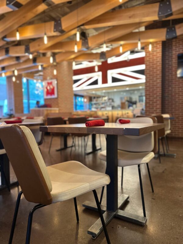 South Loft custom dining table with upholstered chairs in a modern restaurant with a Union Jack flag decor.