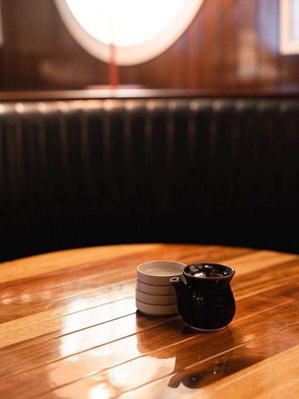 South Loft custom polished wooden table with small tableware in a booth with soft lighting.