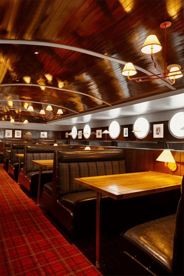 South Loft custom booth seating with wooden tables and soft lighting in a nautical-themed dining area.