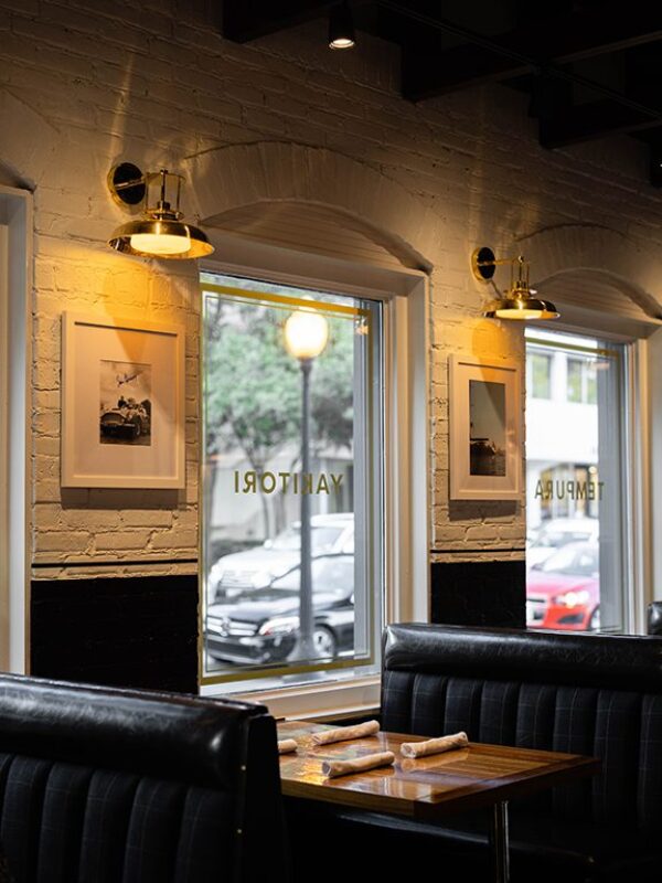 South Loft custom booth seating with a wooden table near large windows and framed wall art.