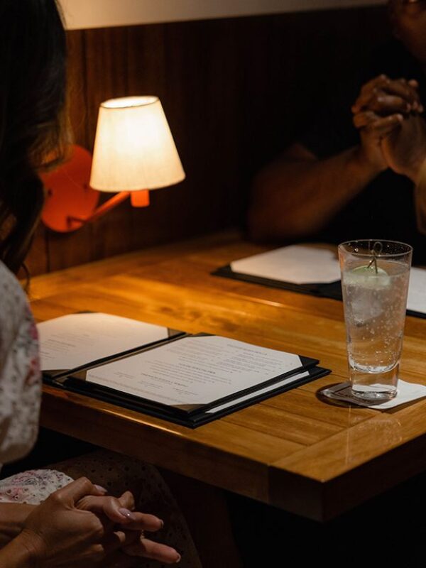 South Loft custom wooden restaurant table with menus, a drink, and soft lighting.