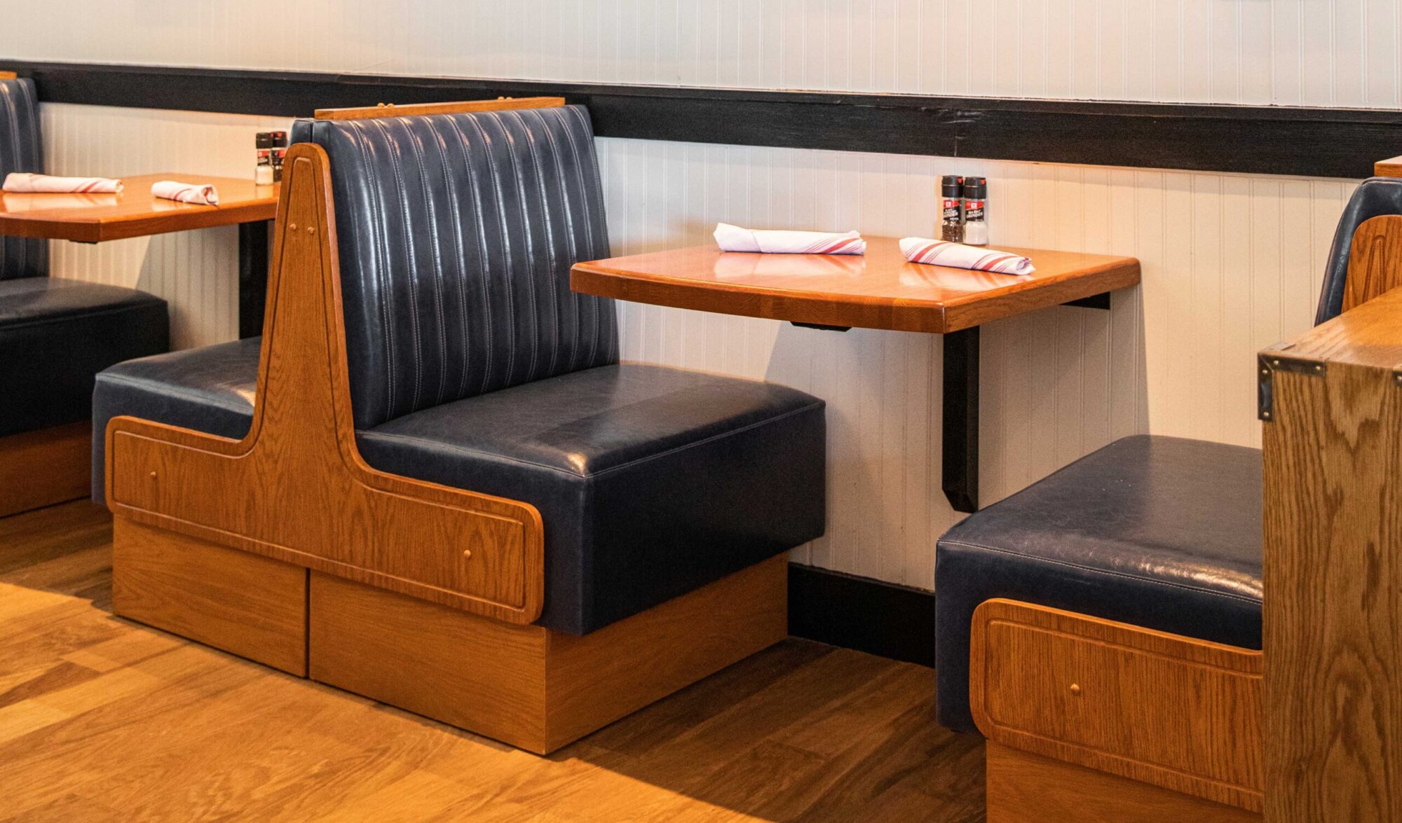 A 255 series base and table are paired with wooden booth seating inside a upscale restaurant.