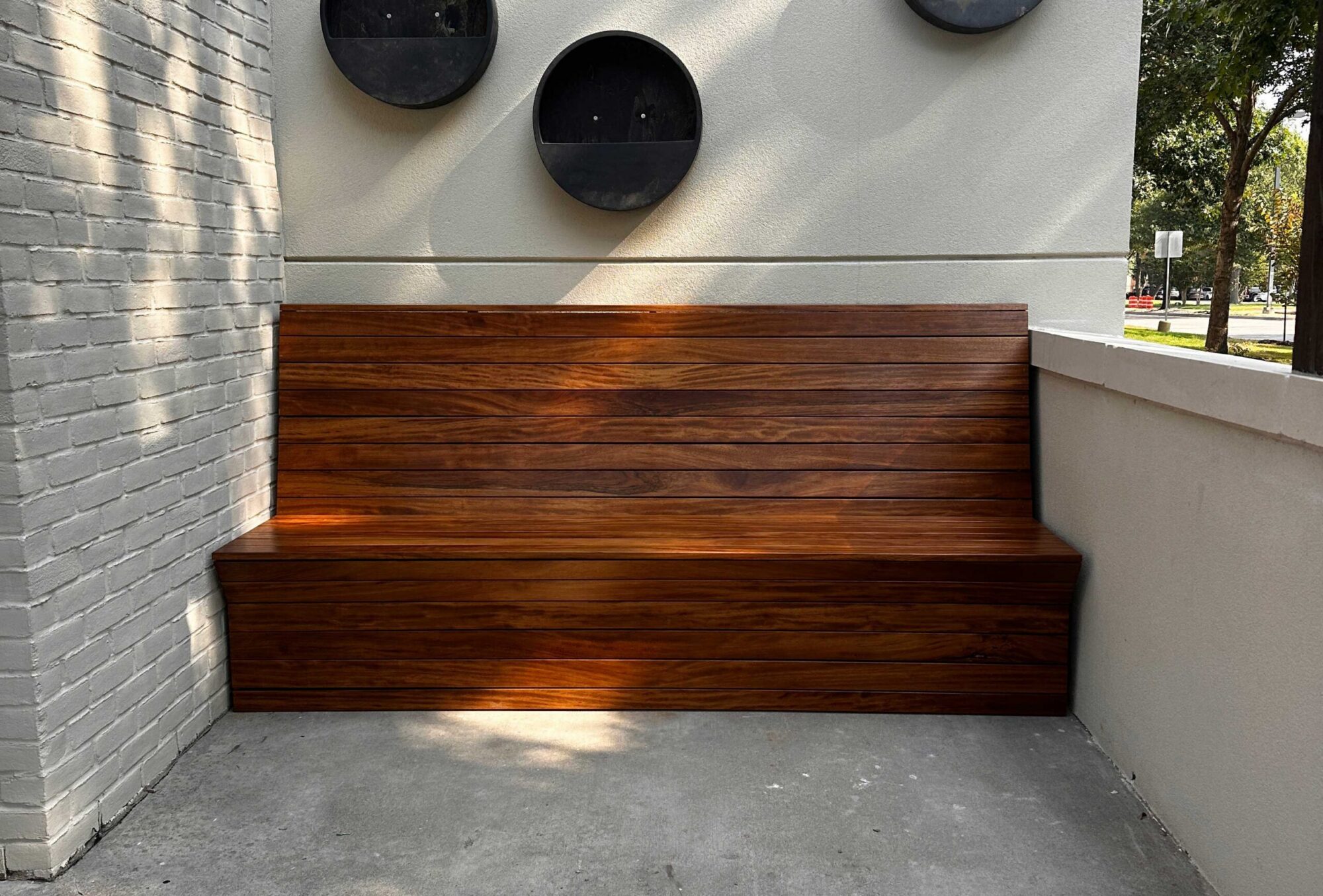 A SouthLoft made wooden bench seating sits in a cubby of a outdoor eatery.