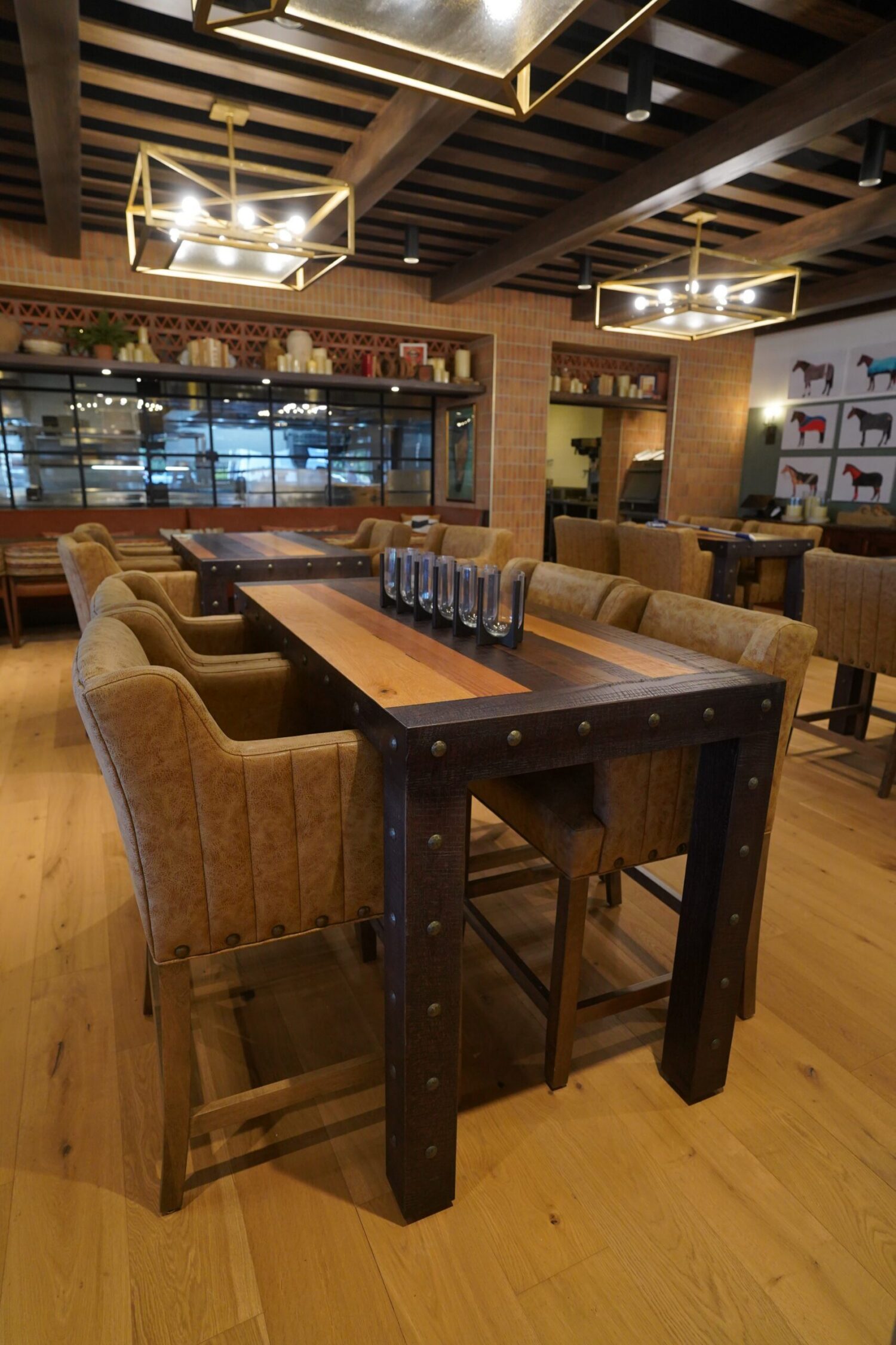A communal dining table with seating is in a large but dark dining room