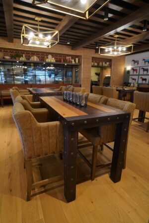 A communal dining table with seating is in a large but dark dining room
