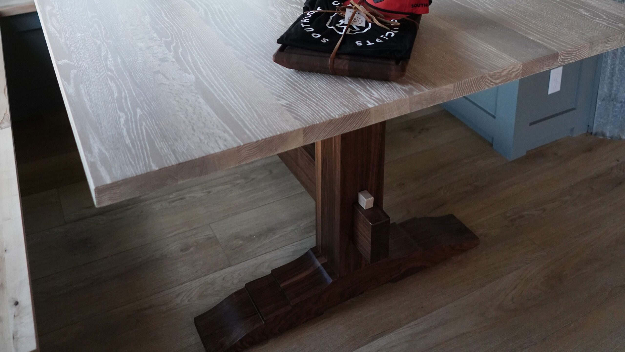 A custom residential table built by SouthLoft sits inside a client's home with a SouthLoft hat and shirt sitting on top.